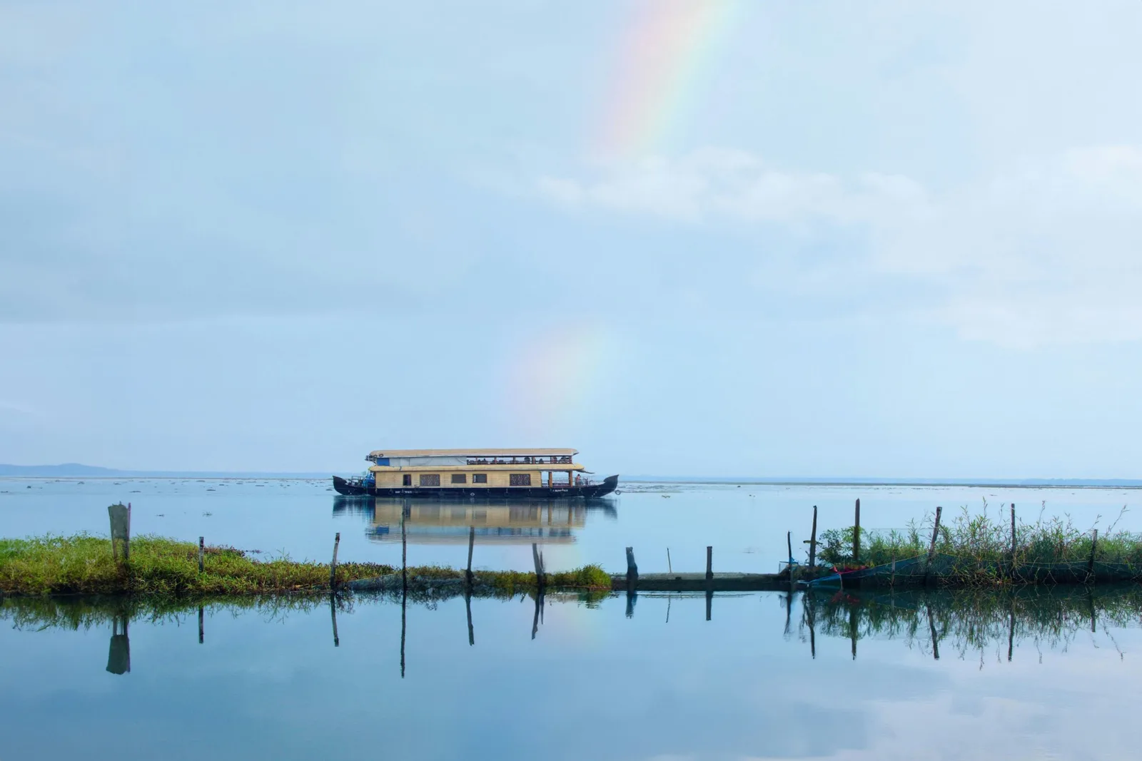 Traditional houseboat on  Kumarakom, Kerala backwaters with a rainbow in the sky.