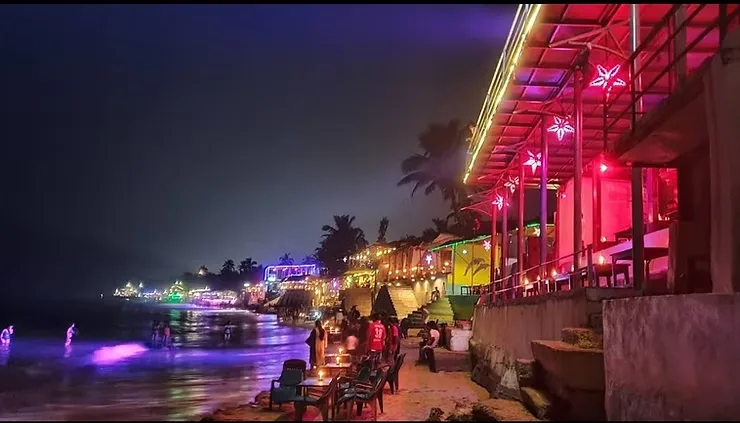 Lively beachside nightlife in Goa with neon-lit shacks, candlelit tables on the sand, and crowds enjoying the vibrant party atmosphere by the sea.