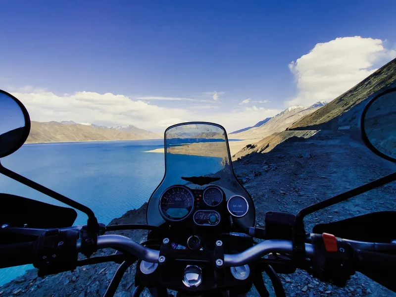 Enfield bike cruising along a high-altitude pass in Ladakh, capturing the essence of a classic Himalayan road trip.