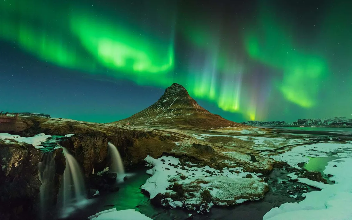 Aurora Borealis over a glacier and rugged landscape in Iceland